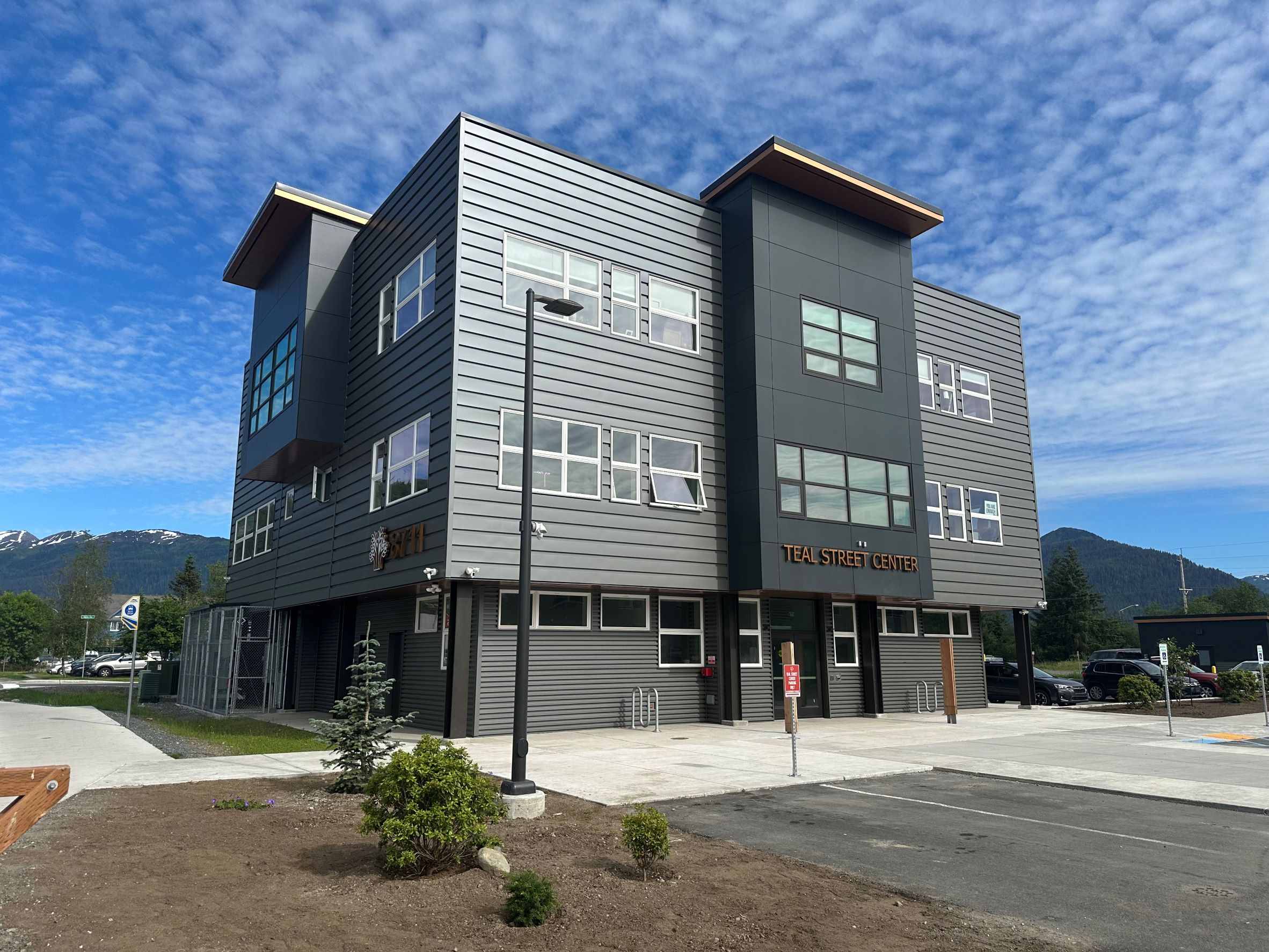 Teal Street Center, a grey three story office building, on a blue sky day.